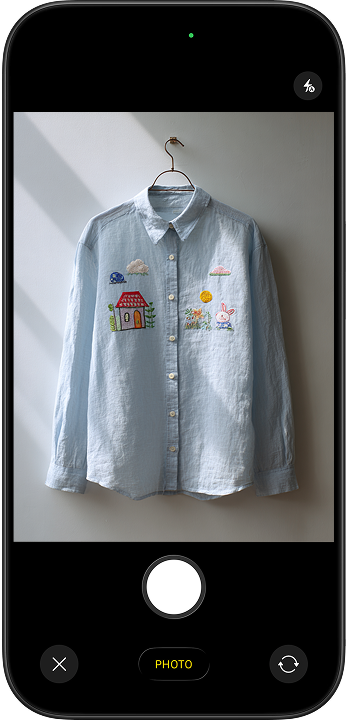 The starting point: a basic iPhone photo of a light blue embroidered shirt on a hanger against a plain wall