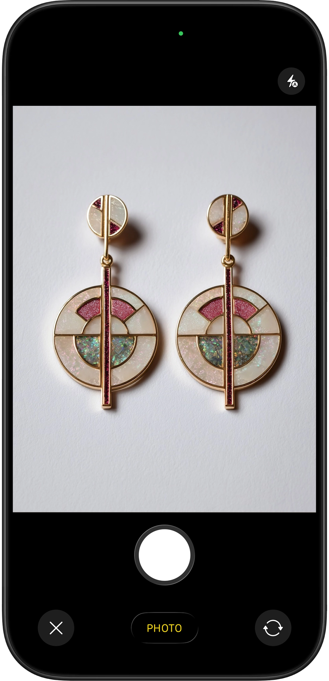 A basic phone photo of a pair of earrings lying on simple background in ordinary home lighting — the raw input photo